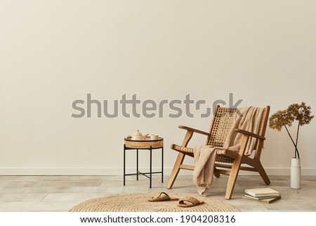 Neutral concept of living room interior with design wooden armchair, round carpet, dried flowers in vase, slippers, decoration and elegant personal accessories. Template. Copy space.