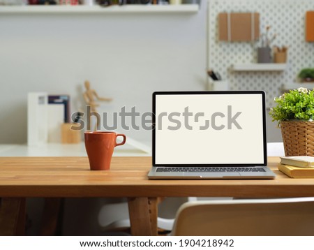 Close up view of office desk with laptop, mug, stationery and supplies on wooden table, clipping path