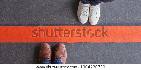 Boundary, quarantine, social distancing and differences concept. Man and woman standing opposite of each other, divided by a thick red line. Wide angle view, copy space. Royalty-Free Stock Photo #1904220730