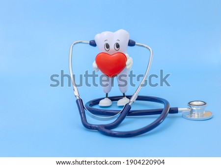 cartoon model of a tooth with a heart and a stethoscope on a blue background. Monitoring the health of the oral cavity