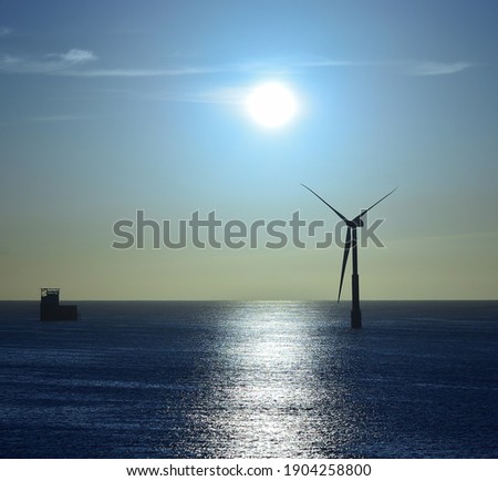 Turbine in the sea and marine platform with intense sun and blue sky