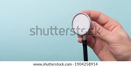 Medical stethoscope in a doctor hand on light blue background. Medicine and healthcare concept. Copy space, close up, banner