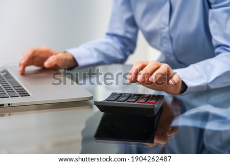 Woman working with calculator in the office 
