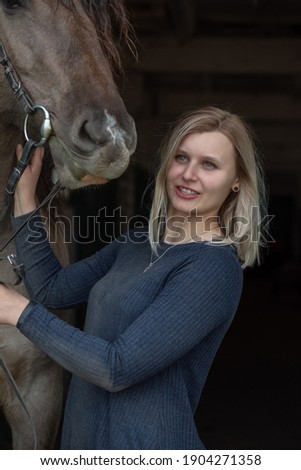 Beautiful blonde girl next to a horse at the ranch.