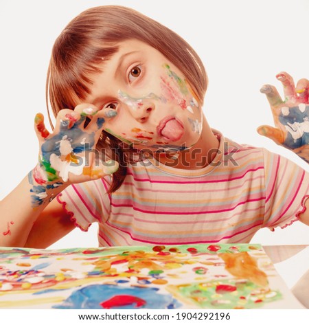 Funny image of young beautiful attractive child girl painting picture with colorful painted hands. 
