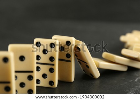 White domino tiles falling on dark grey table