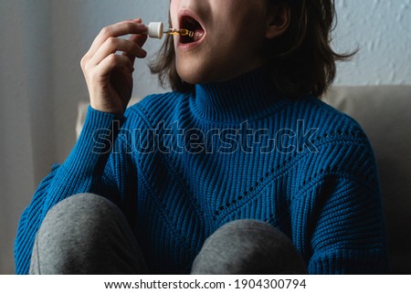 Young woman taking cbd oil under tongue - Alternative medicine concept - Focus on dropper Royalty-Free Stock Photo #1904300794