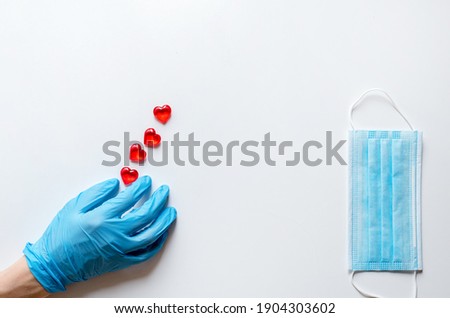 The hands of a doctor in medical gloves on a white background holding stones in the form of a heart. The concept of a healthy heart