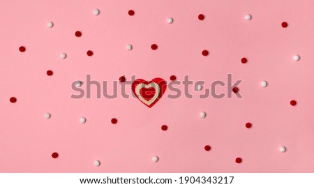 Valentine's day top view flat lay. Silver bow and ribbon with red hearts on gently pink background. Holiday celebration gift concept. Copy space for text.