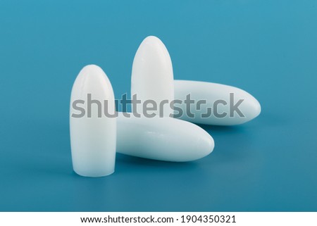 Medical suppository on a blue background.White rectal and vaginal unpacked candles.Soft focus.Concept of treatment of female diseases,hemorrhoids,cracks,anti-inflammatory,from temperature. Royalty-Free Stock Photo #1904350321