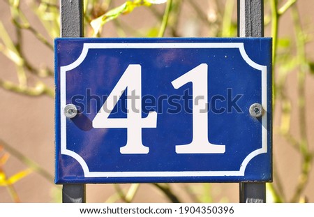 A blue house number plaque, showing the number forty one (41)  