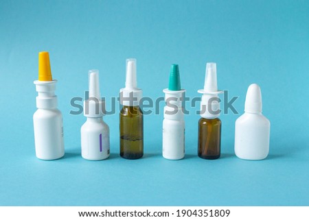 Bottles of nasal spray standing in line on blue background, medicine flat lay, treatment for colds