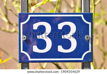 A blue house number plaque, showing the number thirty three (33)  