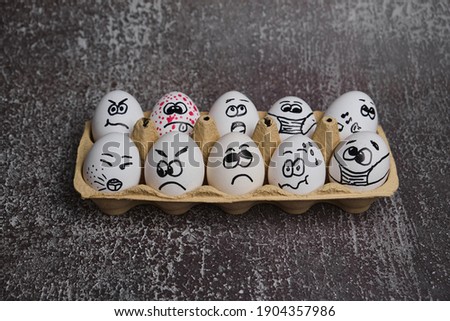 Easter holiday eggs in masks. Tray of white eggs with drawn funny faces wearing medical masks at Easter holiday during coronavirus epidemy close up