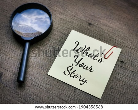 Selective focus side view text What is your story on sticky note with magnifying glass on wooden background.