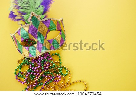 Mardi gras or carnival mask with beads on yellow background. Venetian mask. Royalty-Free Stock Photo #1904370454