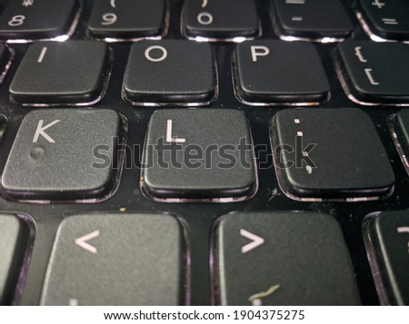 closeup view of backlit black computer keyboard highlighting alphabet L