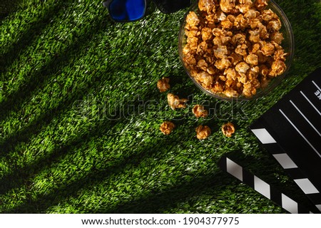 Popcorn with caramel on the background of the grass .Concept for rest and watching a movie. Screensaver for cinema and films.