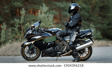 Biker in a helmet and leather protective equipment sits on a motorcycle, a sporty fast motorcycle Royalty-Free Stock Photo #1904396218