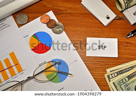 There is a card with the word of STP which is an abbreviation for Segmentation Targeting Positioning on the desk with a laptop, a pen and glasses.