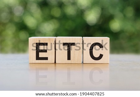 ETC (abbreviation of et cetera) word written on wooden blocks. The text is written in black letters and is reflected in the mirror surface of the table. Royalty-Free Stock Photo #1904407825