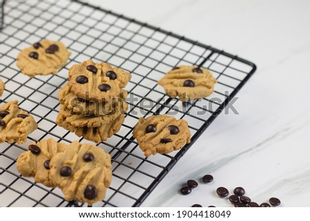 Selective focus of Homemade chocolate chips cookies on black cooling rack. Marble white background. 