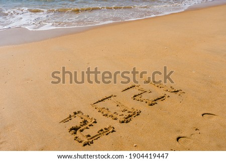 Closeup sign 2021 year numbers written on beach sand background