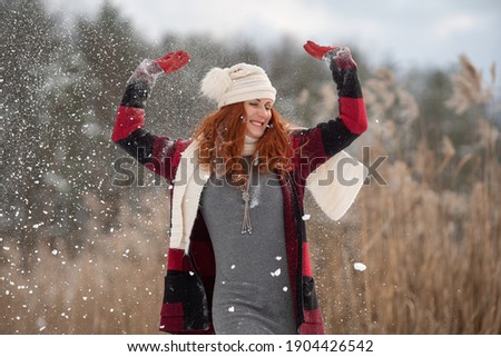 Happy middle-aged woman plays with snow in sunny winter day. Female enjoys winter, frosty day. Winter holidays, woman throws white, loose snow into the air. Walk in winter forest. activity for health