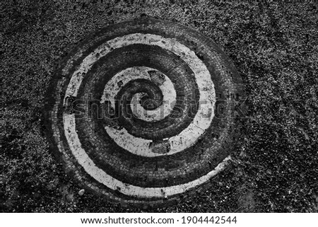 A mosaic depicting a spiral, on a stone floor.