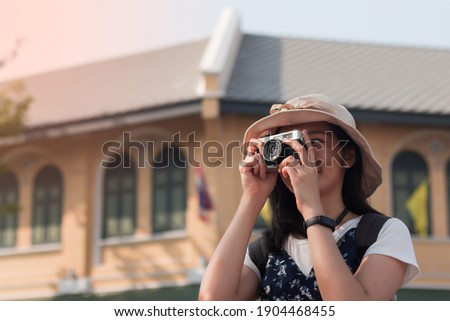 asian woman wearing hat taking photogrape on the street among old city road
