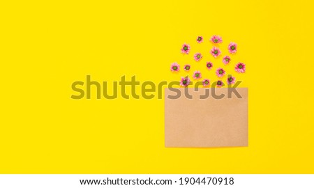 Sheet of craft paper and flowers on yellow background. Clean envelope. Handmade hobby material. Wrapping. Handicraft goods store. Recyclable. Holiday card with copy space, text place. Cute. Eco.