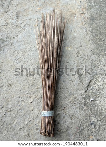 A traditional Indonesian broom made from a bunch of coconut tree branches tied together