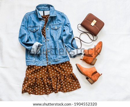 Women's clothing for spring, summer, autumn - denim jacket oversize, polka dot dress, suede chelsea boots and cross body bag on a light background, top view