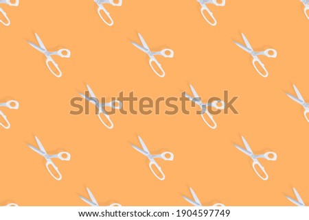 Scissors seamless pattern. Barber scissors against orange background backdrop.