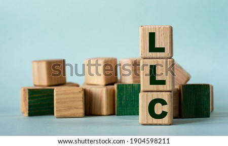 LLC (Limited Liability Company) - acronym on wooden cubes on a background of colored block on a light background. Business concept Royalty-Free Stock Photo #1904598211