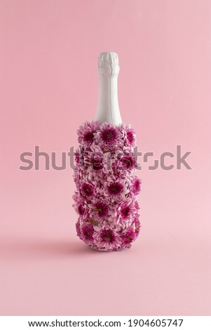 A creative love concept with a bottle of champagne made of flowers on a pink background. Valentines or woman's day idea