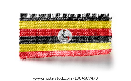 Uganda flag on a piece of cloth on a white background