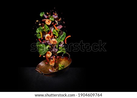 Flying wok ingredients - shrimp, vegetables, pak choi leaves, onions and peanuts. Asian food delivery. Chinese recipes. Wok preparation ingredients. Copy space Royalty-Free Stock Photo #1904609764