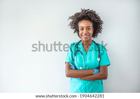 Portrait of a nurse standing in a hospital. Female nurse looking towards camera, wearing blue scrubs, arms crossed. Medical professional working in hospital. Attractive female doctor at work.