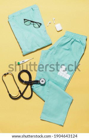 modern medical clothes for doctors and nurses laid out on a paper background, top photo