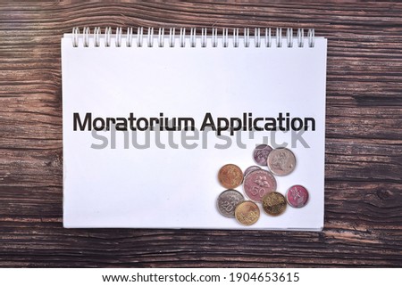 Selective focus image of coin with Moratorium Application wording and wooden background. Business and economy concept