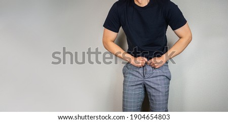Wearing tight pants, Man trying to hook the pants as gaining weight Royalty-Free Stock Photo #1904654803