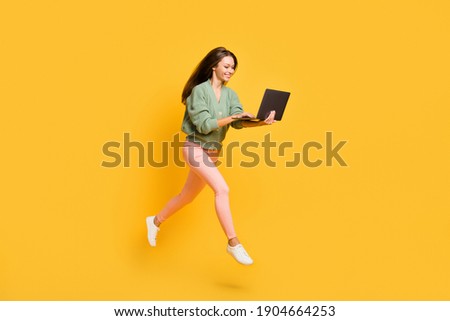 Full size profile side photo of young happy cheerful smiling girl run in air work in laptop isolated on yellow color background
