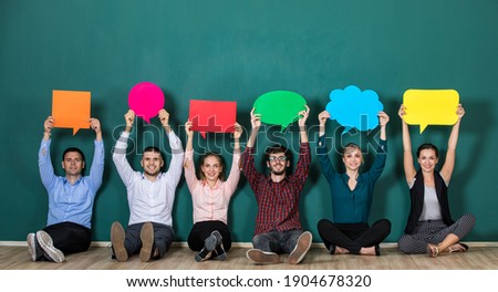 Group of six business people team sittiing together and holding colorful and different shapes of speech bubbles Royalty-Free Stock Photo #1904678320