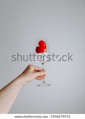 Happy Valentines Day 2021 - a heart shape in a glass of wine. Love in Corona time. Covid-19 pandemic concept. Coronavirus Valentine. Woman hand holding a glass of wine with red heart.