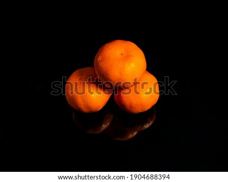 Orange tangerine fruit on a black background. Orange tangerine. Green leaf. Fruit juice. Collection of garden citrus fruits. Agriculture. Vegetarian food. Photo of food. Background.