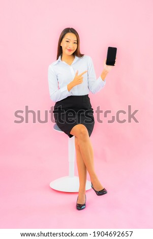 Portrait beautiful young asian woman use smart mobile phone on pink isolated background