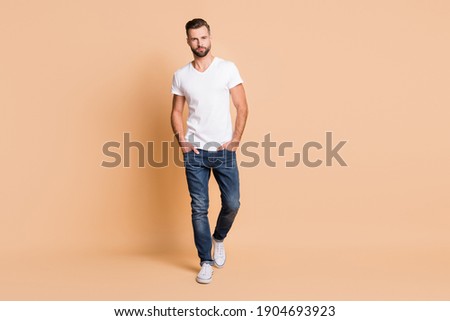 Full length body size view of nice content attractive tall macho guy going isolated over beige pastel color background Royalty-Free Stock Photo #1904693923