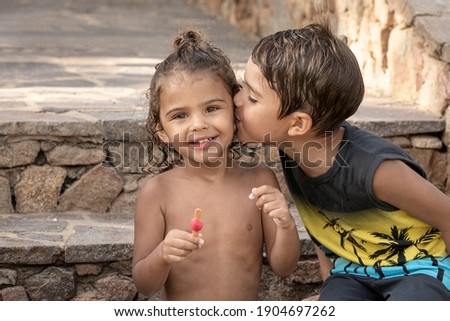 Brazilian little brother kisses his 2-year-old sister while eating a popsicle in the summer