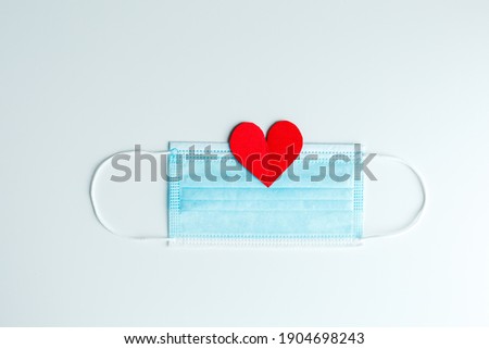Red paper hearts for Valentine's day and blue face masks on a white background 